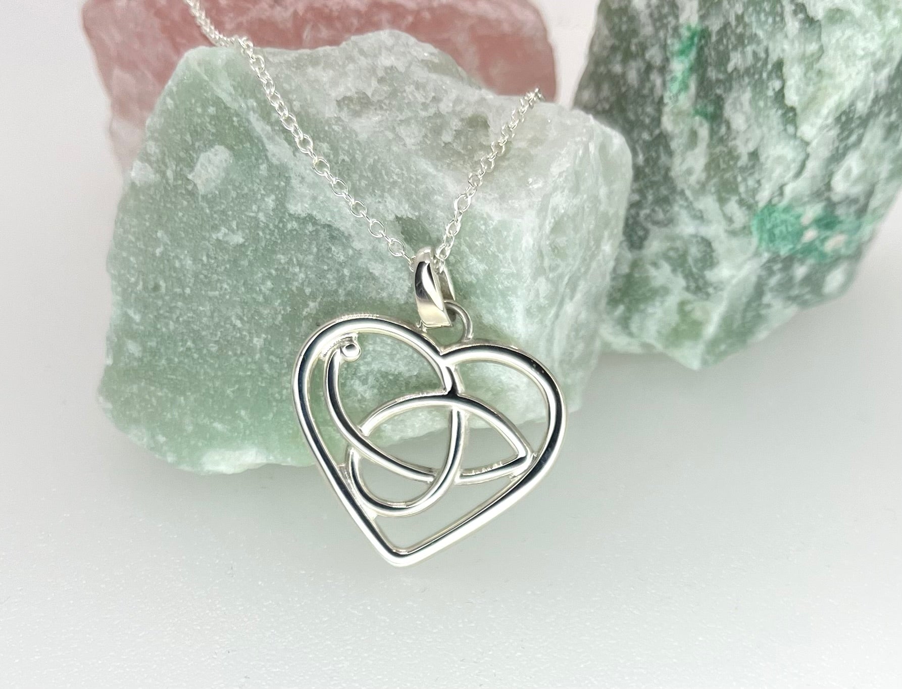 Silver necklace with a heart-shaped pendant on a light background