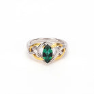 A two-tone sterling silver and yellow gold ring featuring a marquise-cut green emerald gemstone at the center, set against a plain white background.