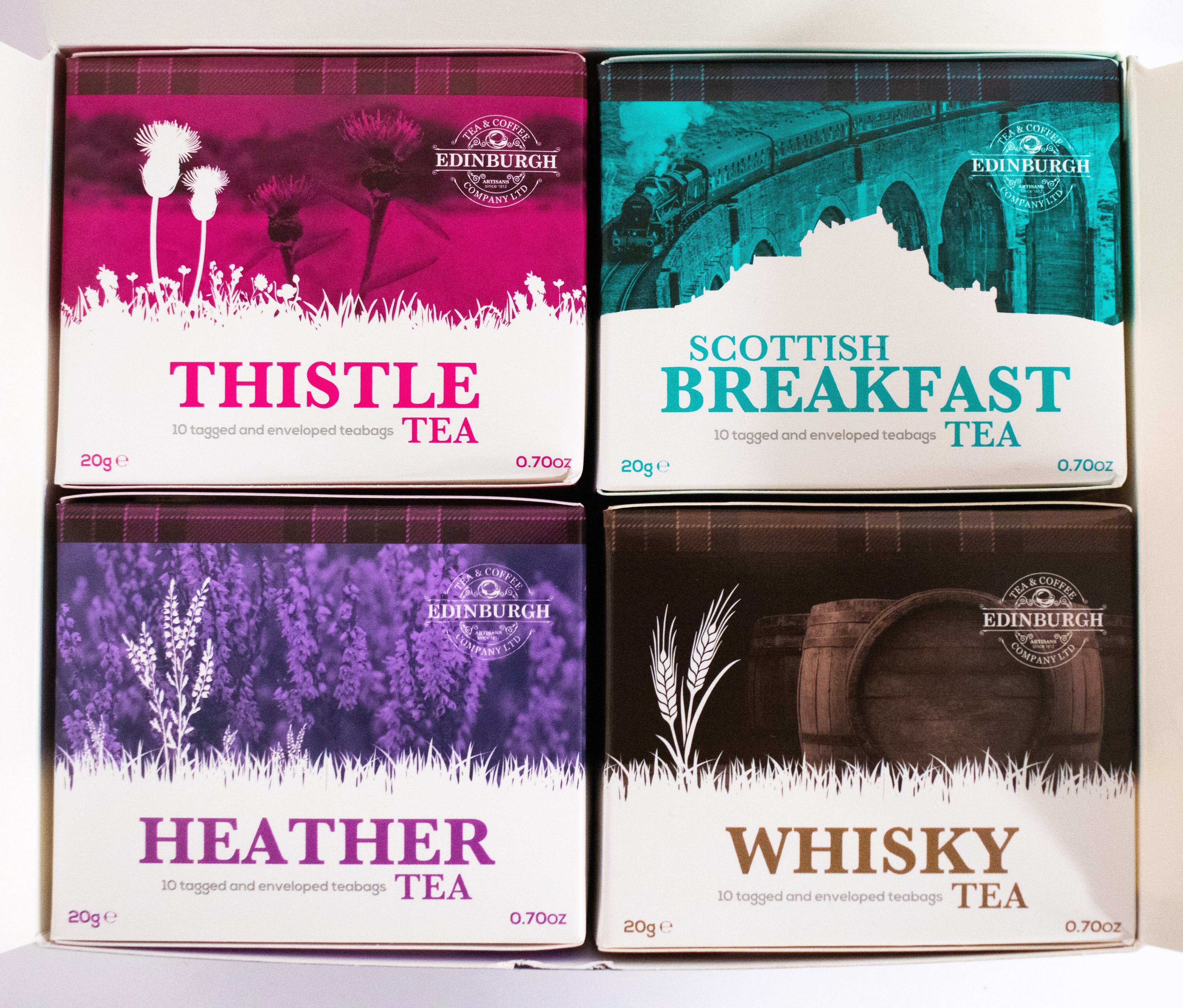 Four boxes of Edinburgh tea with different flavors on a white background