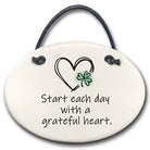 Decorative hanging plate with a heart and clover design and text 'Start each day with a grateful heart.'