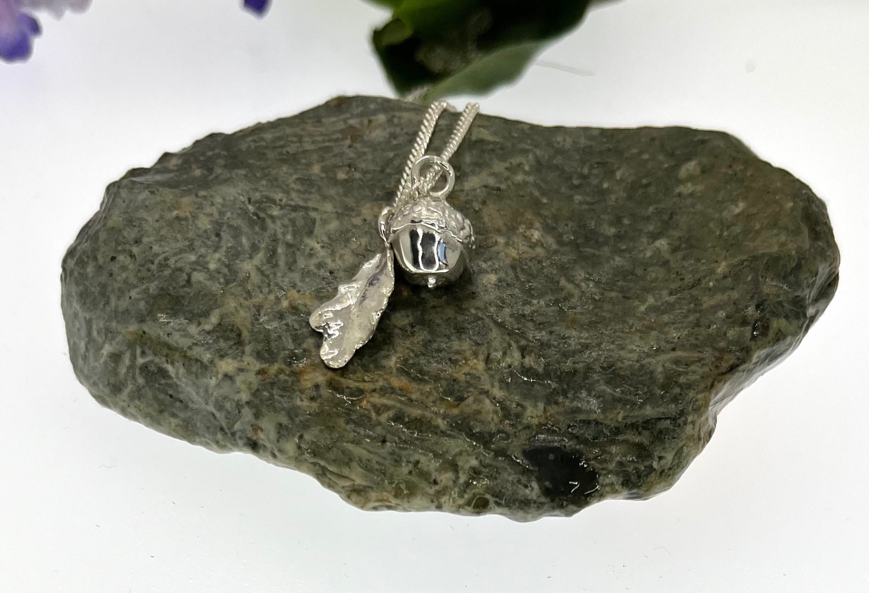 Silver pendant with leaf design on a rock