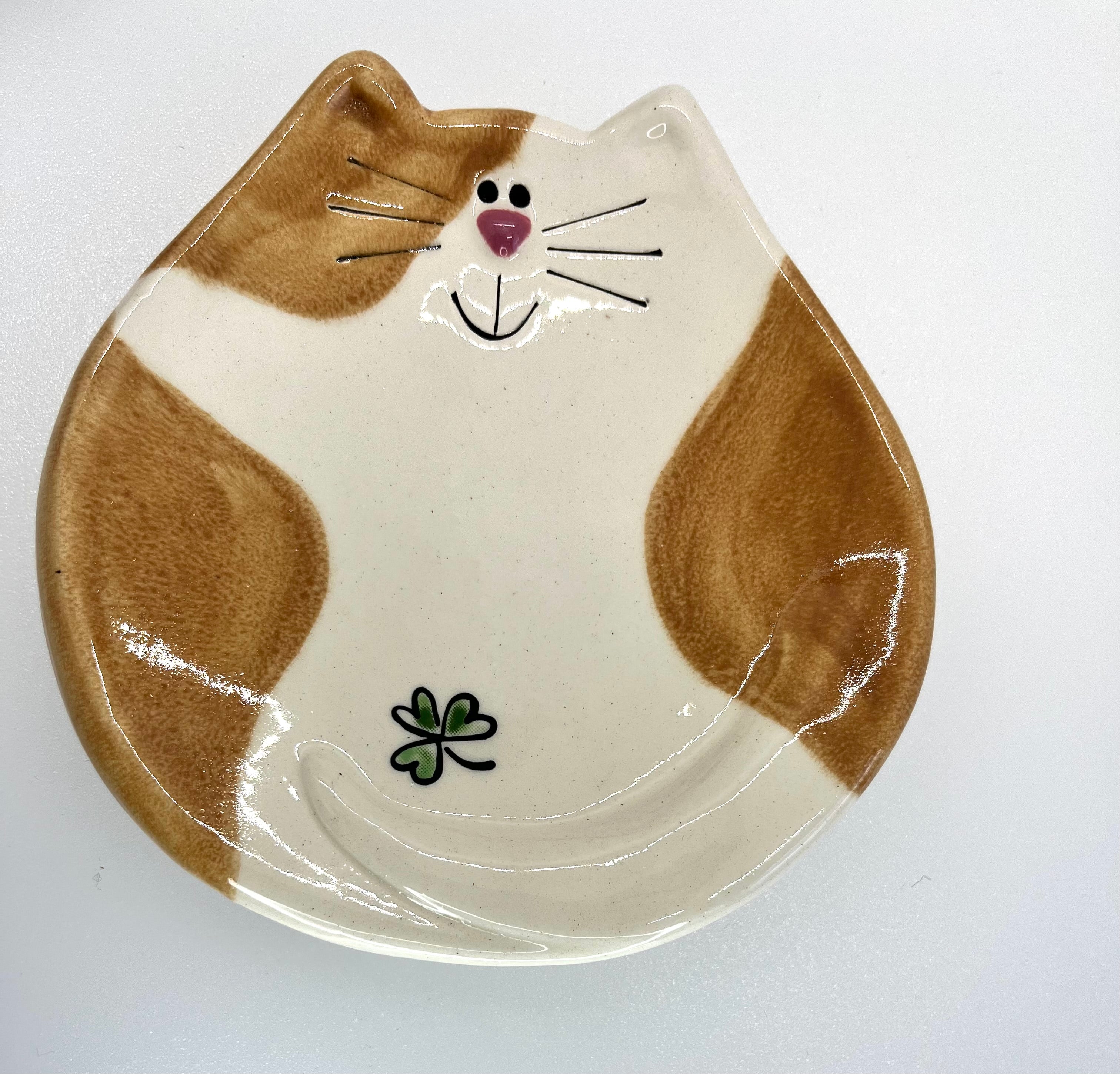 Ceramic plate shaped like a cat face with brown and white design on a white background