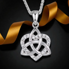 A silver Celtic knot pendant necklace with clear crystals, displayed on a black background with a gold ribbon.
