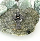 Silver Celtic cross pendant on a rock