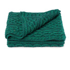 Folded teal knitted blanket on a white background