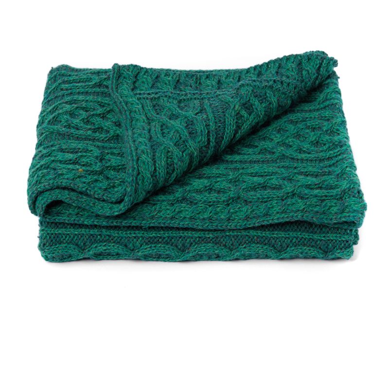Folded teal knitted blanket on a white background
