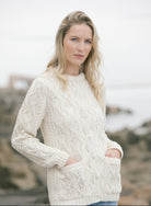 Woman wearing a white knitted sweater against a blurred natural background