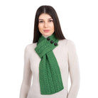 Woman wearing a green knitted scarf with buttons on a white background