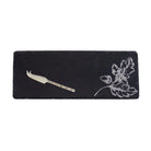 Black slate cheese board with floral design and knife on a white background