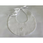 White bib with a cross design and satin ribbon on a light gray background