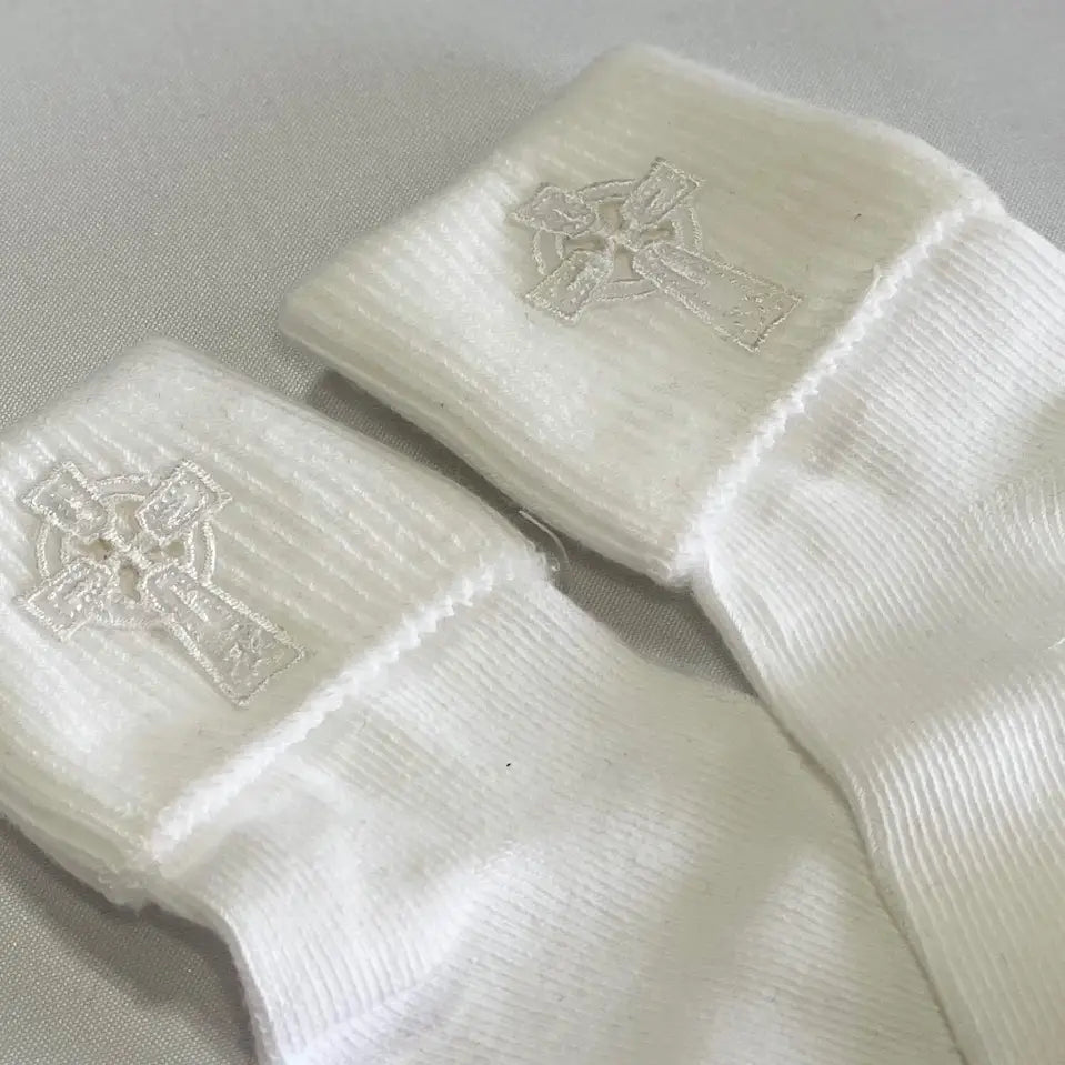 White baby socks with Celtic cross design on a light gray background
