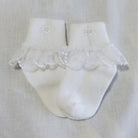White baby socks with lace trim on a light gray background