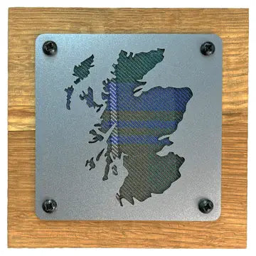 A square metal plaque featuring the silhouette of Scotland with a blue and green tartan plaid pattern, mounted on a square wooden board with four black screws in the corners.