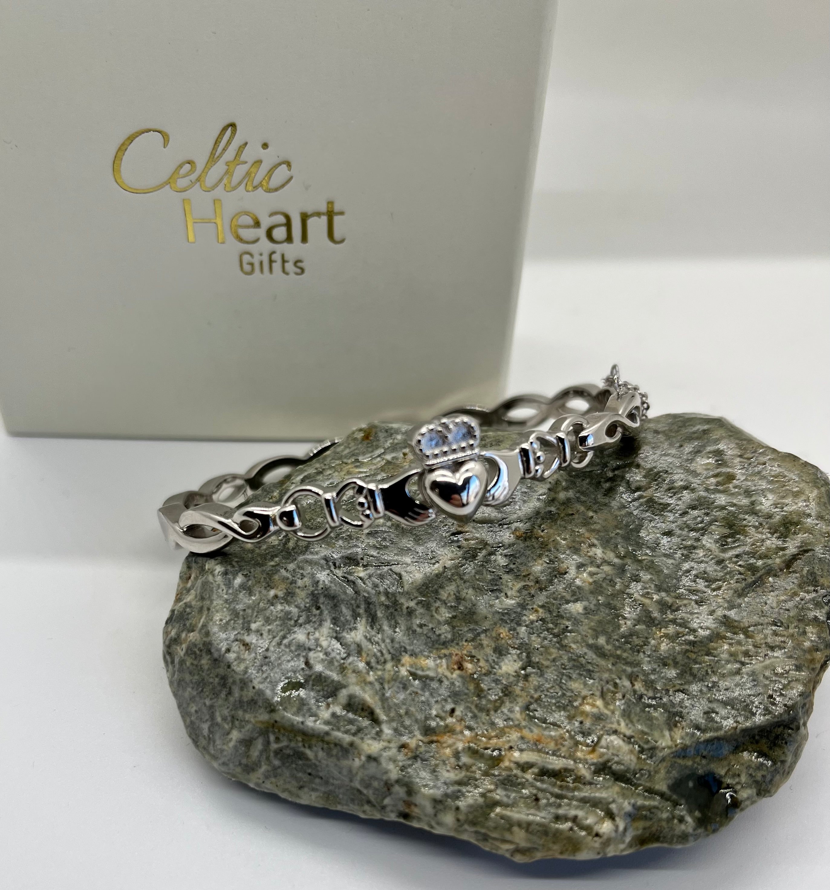 Silver bracelet with heart and infinity symbols on a rock with 'Celtic Heart Gifts' box in the background.