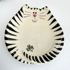 Ceramic plate with black and white striped design resembling a cat face on a white background