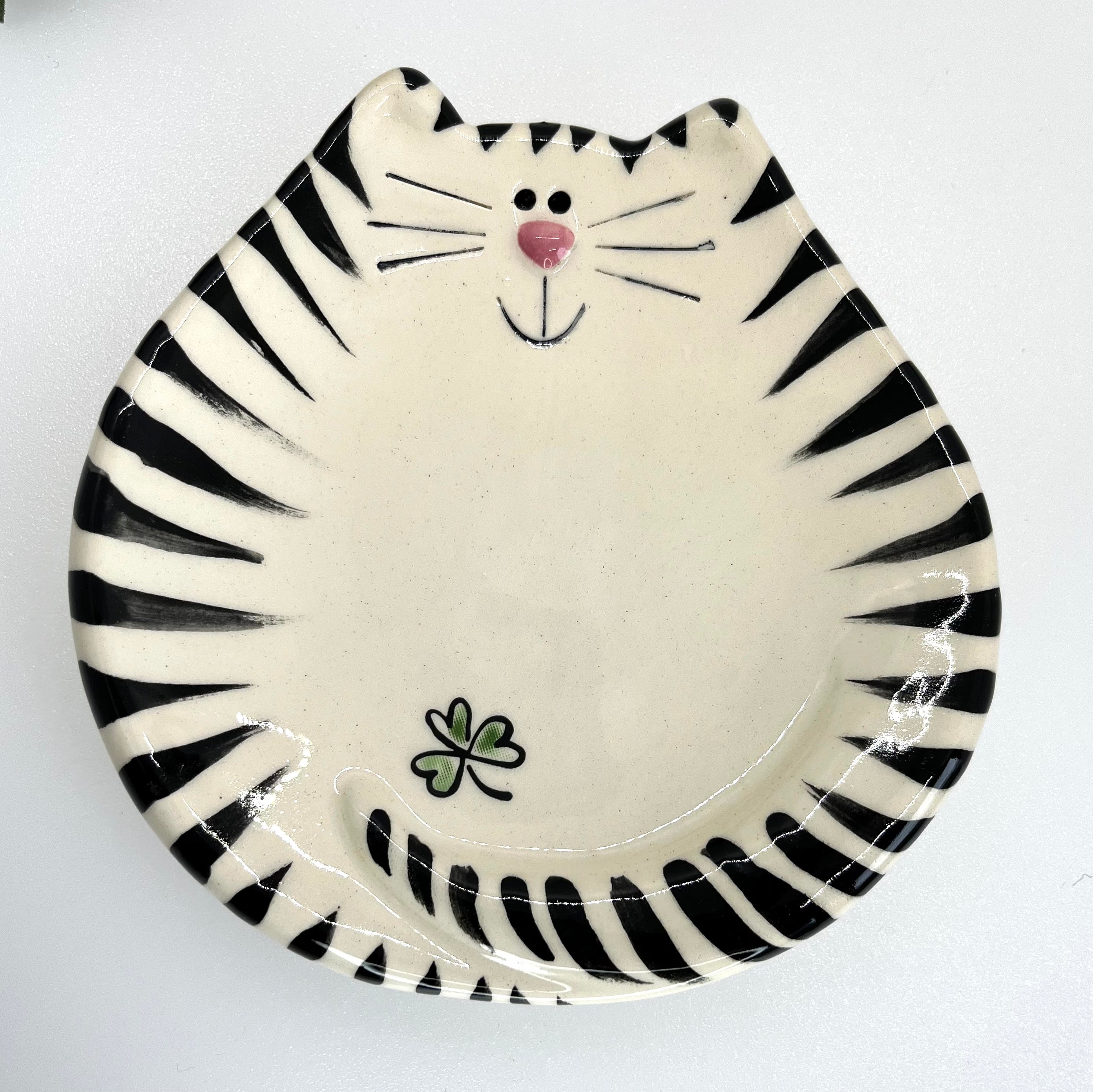 Ceramic plate with black and white striped design resembling a cat face on a white background