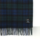 Plaid blanket with fringes and a brand label on a white background