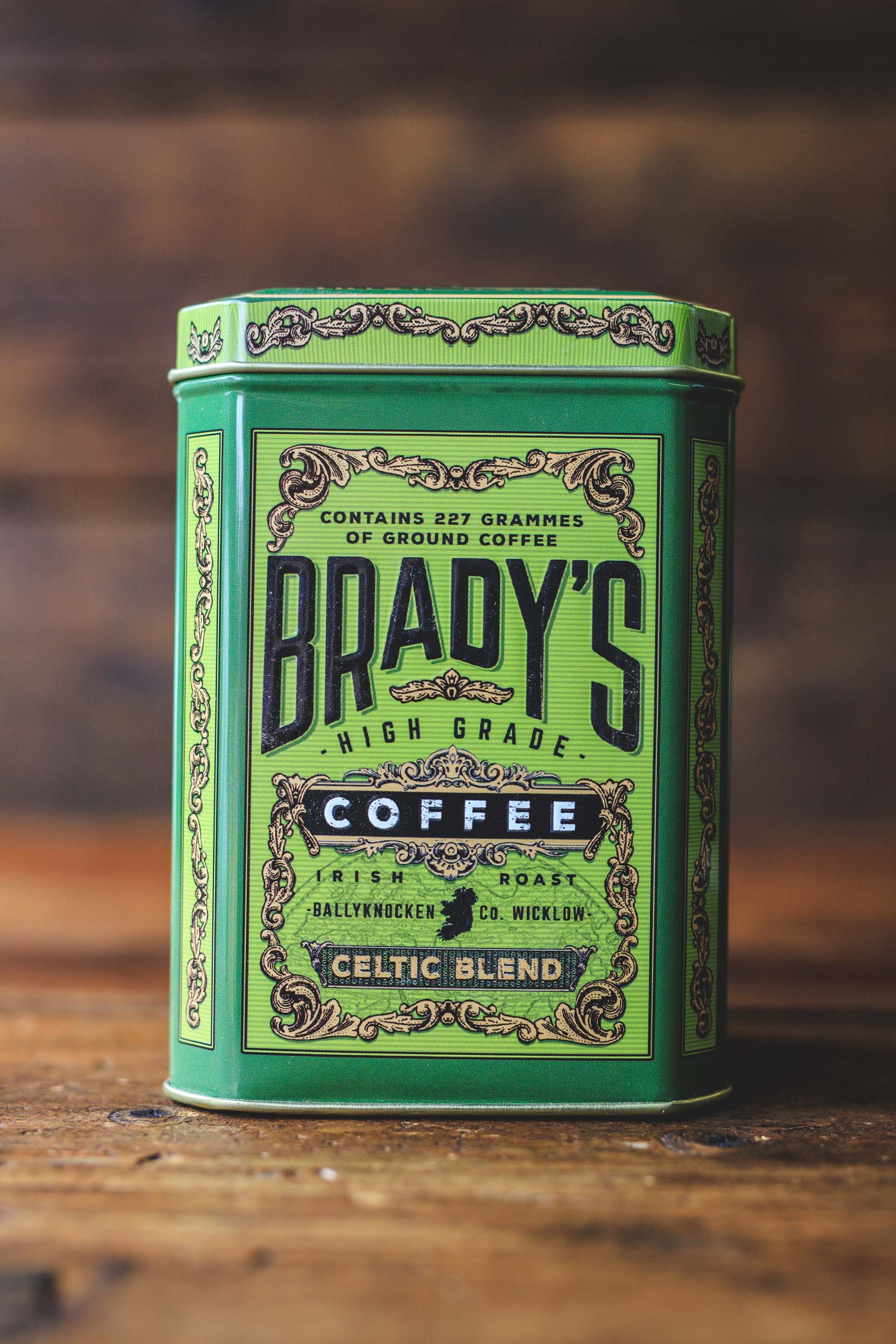 Green canister of Brady's High Grade Coffee on a wooden surface with a blurred background