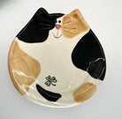 Ceramic plate shaped like a cat with black, brown, and white design on a white background
