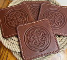 Brown leather coasters with Celtic knot design on a woven mat