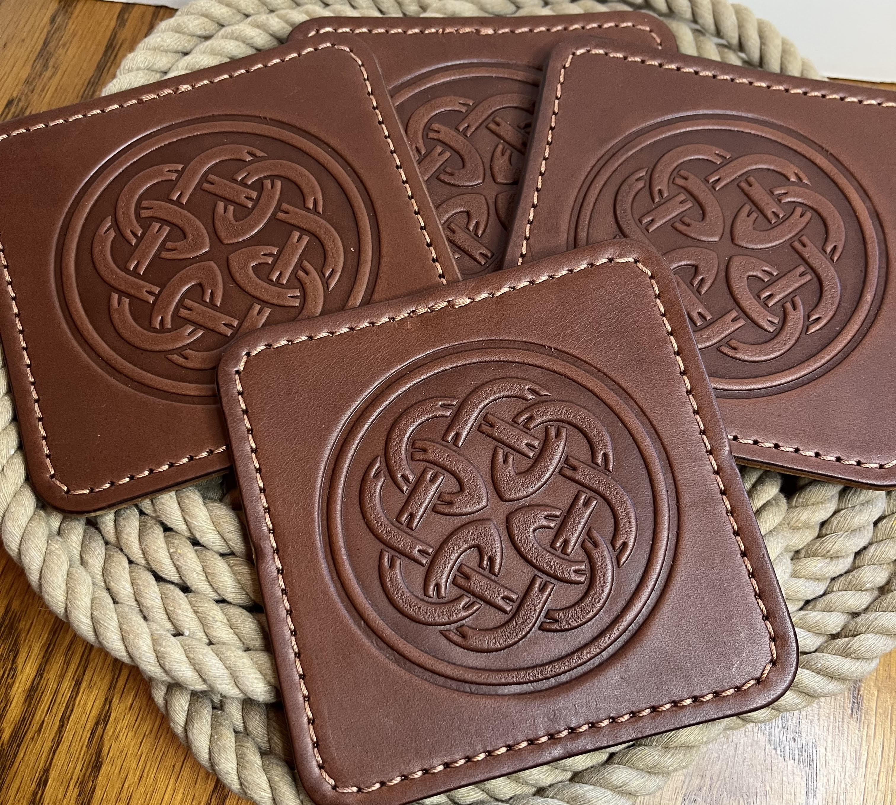 Brown leather coasters with Celtic knot design on a woven mat