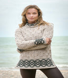 Woman wearing a patterned sweater standing on a beach.