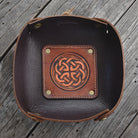 Brown leather tray with Celtic knot design on a wooden surface