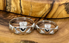 Two silver Claddagh rings on a wooden surface
