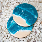Two blue and beige coasters on a pebble surface