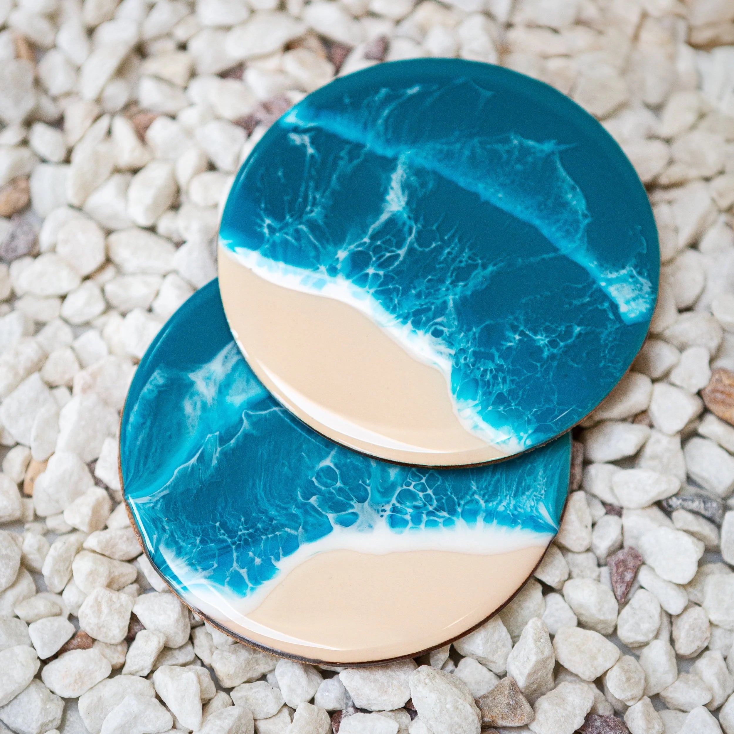 Two blue and beige coasters on a pebble surface