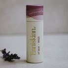 Lip balm container with purple lid on a neutral background