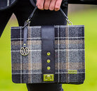 Plaid handbag with visible brand logo held by a person against a blurred green background