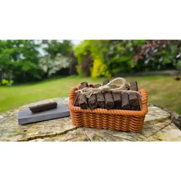 A basket of dark chocolate squares tied with twine sits on a stone surface outdoors, with a blurred garden background.