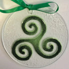 Decorative glass ornament with green and white spiral design on a white background