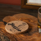 Cork coaster with golf design on a wooden surface next to a glass of beer.