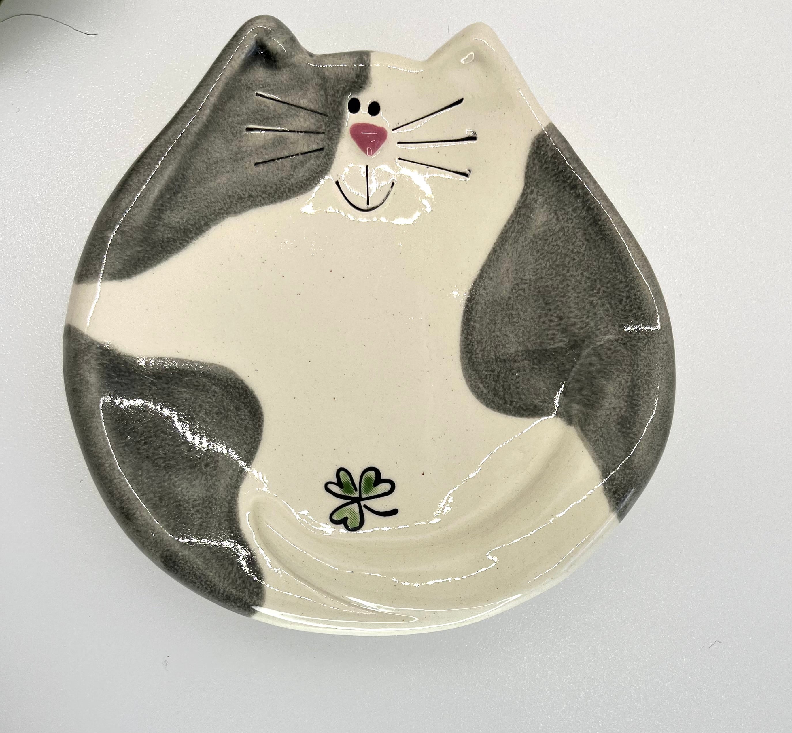 Ceramic plate shaped like a cat's face with gray and white design on a white background