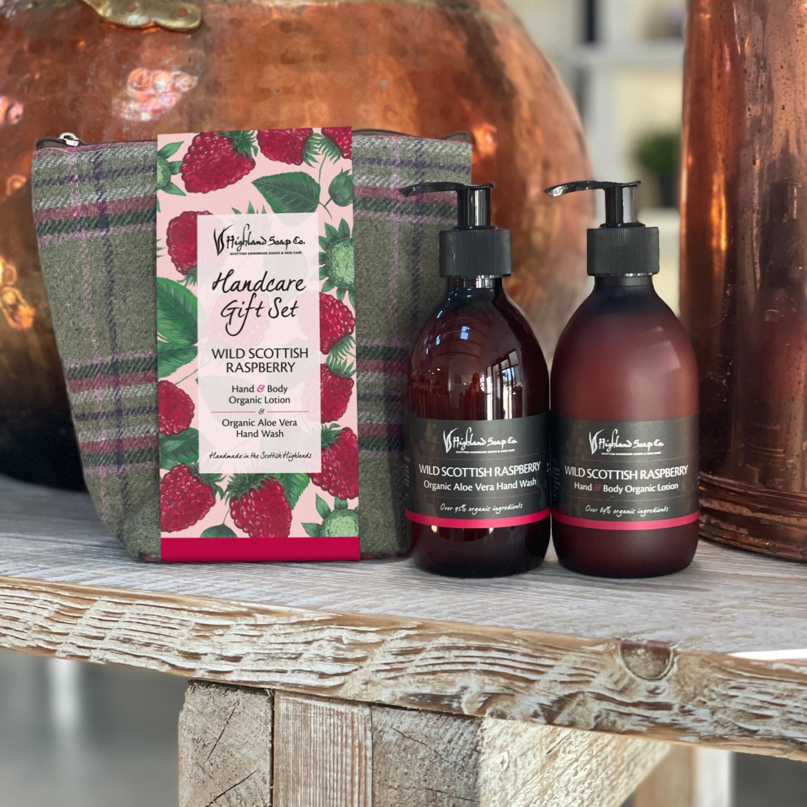 Handcare gift set with two bottles and a wrapped package on a wooden surface.