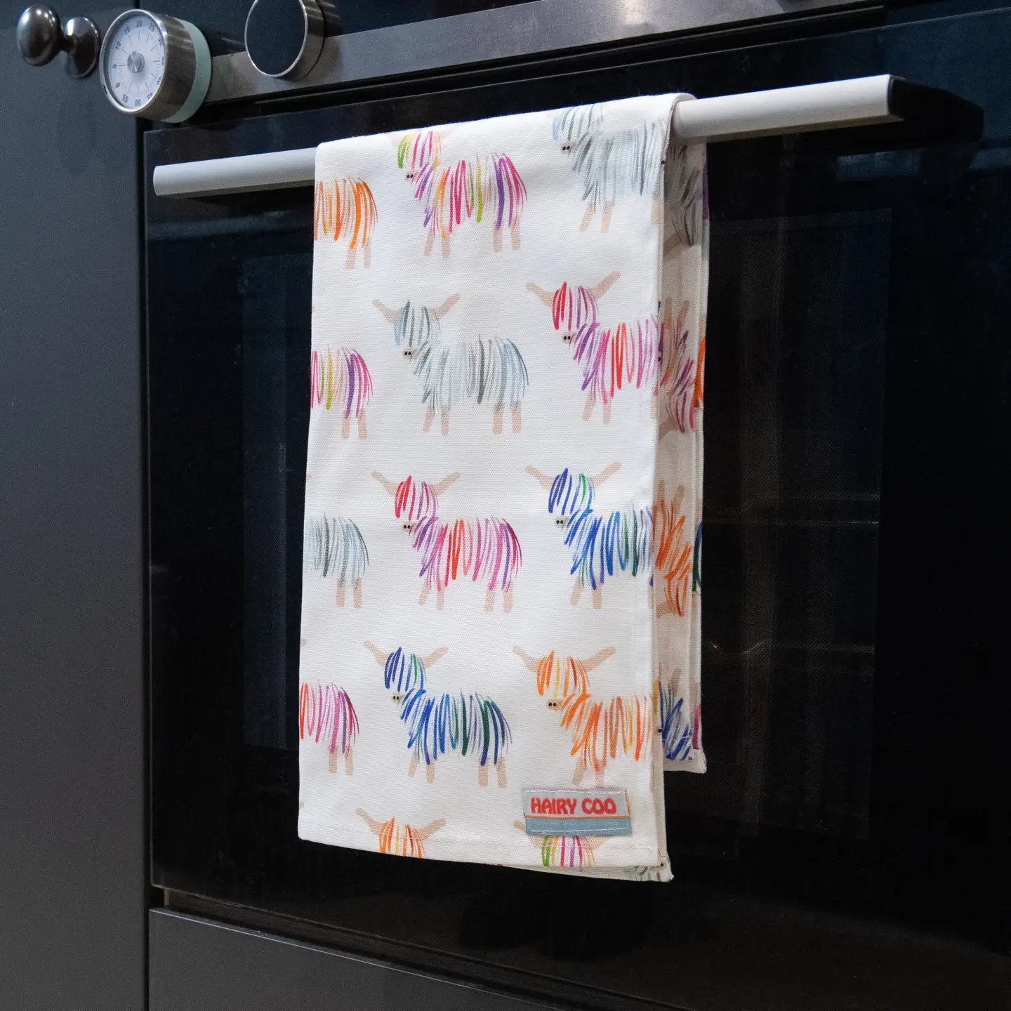 Colorful cow patterned tea towel hanging on an oven handle