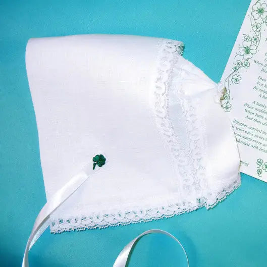 White baby bonnet with green embroidery on a turquoise background