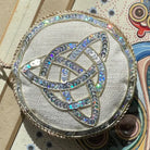 Round, embellished Irish linen ornament with intricate design on a textured surface