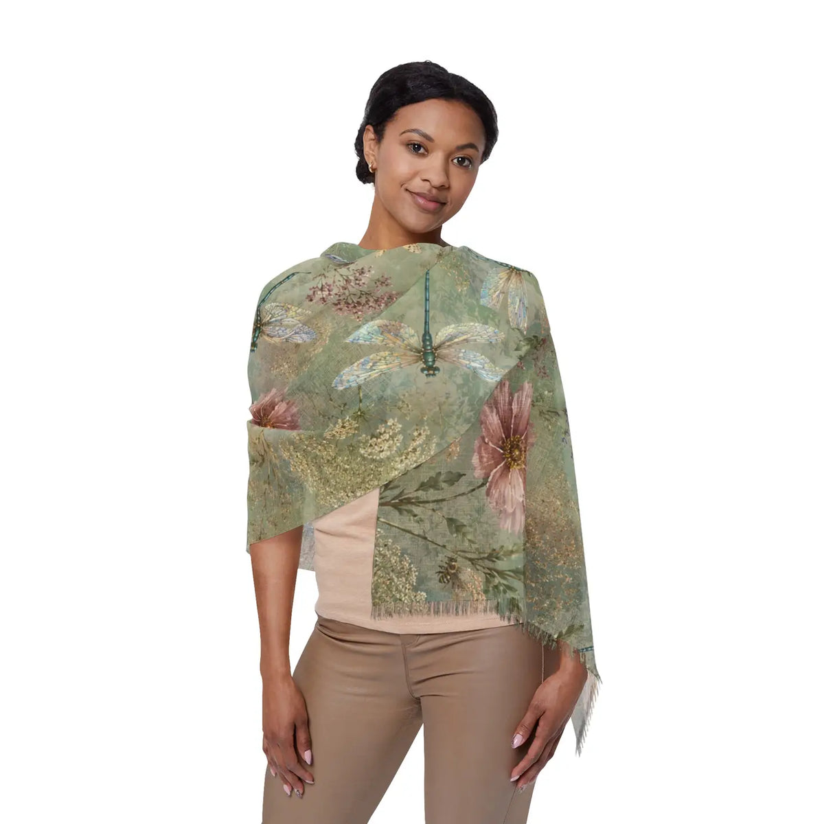 A woman modeling a lightweight draped wrap or shawl with a botanical print in muted sage green, dusty pink, and beige tones, paired with a beige top and tan pants against a plain white background.