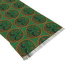 A green woven textile scarf with a repeating circular Celtic-style tree motif in black and gold, finished with white fringe on one end, photographed on a white background.