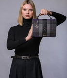 Woman holding a gray and purple handbag against a gray background