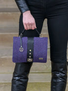 Person holding a purple textured handbag with a wooden background