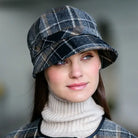 Woman wearing a plaid hat and turtleneck against a neutral background
