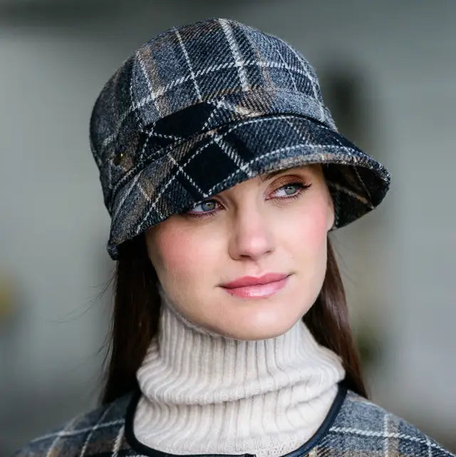 Woman wearing a plaid hat and turtleneck against a neutral background