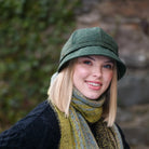 Woman wearing a green hat and colorful scarf outdoors