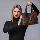 Woman holding a red and black plaid handbag against a gray background