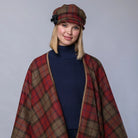 Woman wearing a plaid cape and hat on a gray background