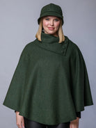 Woman wearing a green cape and matching hat against a gray background